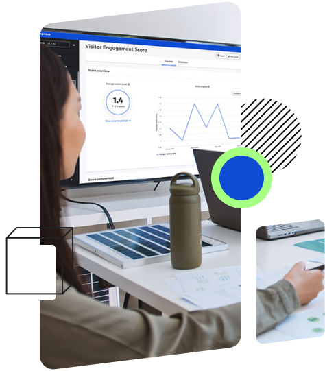 A person is sitting at a desk looking at a monitor displaying a 'Visitor Engagement Score' screen with graphs and data.