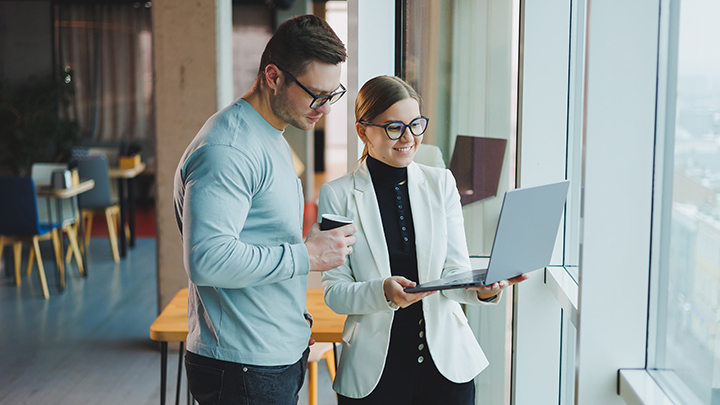 Two people working together looking at a project on a laptop.